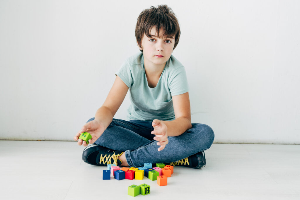 kid with dyslexia sitting on floor with building blocks on white background